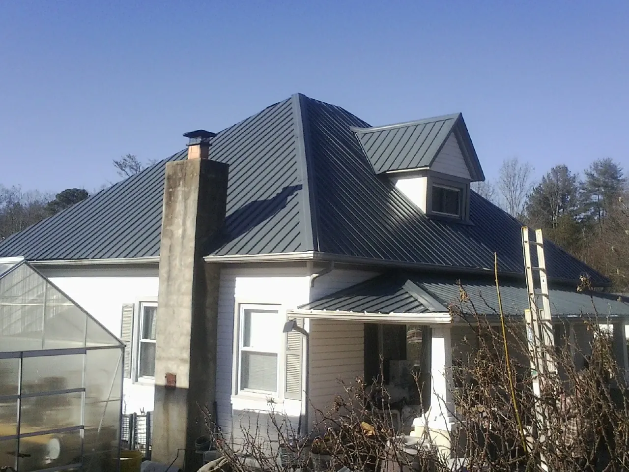Dark blue standing seam metal roof on a white farmhouse with dormer — Slate & Tile Roof Repair by Roofing Brothers in Sammamish
