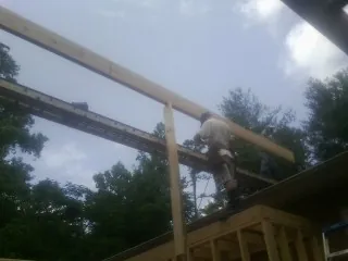 Carpenter setting a ridge beam over a new addition frame — Ice Dam Removal by Roofing Brothers in Sammamish