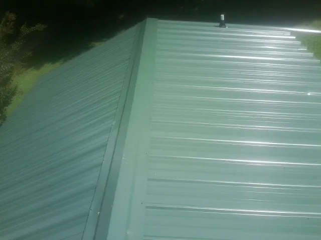 New green metal panels meeting at the ridge of a roof — Flat Roof Repair work by our crew in Sammamish