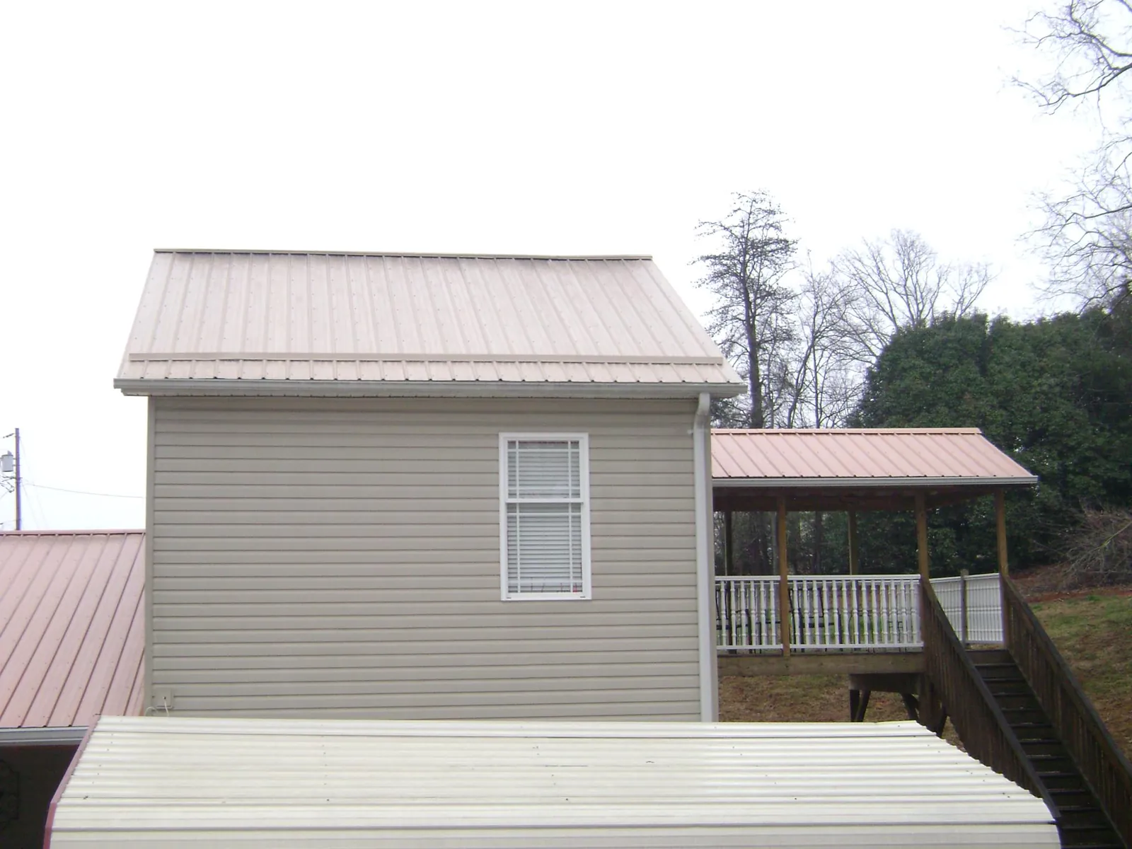 Tan metal roofs on a two story addition and attached porch, from a Roof Replacement job in Sammamish