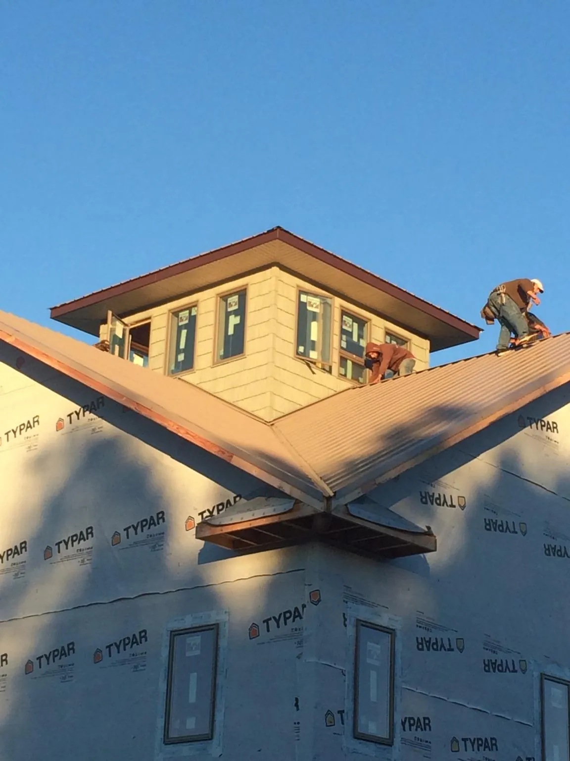 Roofers working around a rooftop cupola on a new metal roof at sunset — Roof Waterproofing in Sammamish by Roofing Brothers